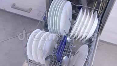 清洁厨房内置洗碗机篮子中的白色盘子和餐具。